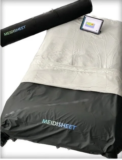 Photograph of the MEIDISHEET smart bed overlay system by NthJEN LLC, featuring pressure-sensitive sensors and connected dashboard for fall and bedsore prevention.