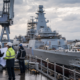 Representative image: Engineers review plans beside a naval vessel under construction, reflecting Babcock International Group’s Type 31 frigate cost challenge, defence execution risk, and broader UK shipbuilding strategy.