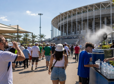 Representative image of fans using water stations outside a sunlit football stadium, highlighting how FIFA World Cup 2026 heat risk, hydration rules and open-air venues are putting fan safety at the centre of tournament planning.