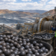Representative image of grinding media, mining equipment and workers at an industrial processing site, illustrating Tega Industries’ Molycop acquisition and global mining consumables expansion.