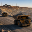Autonomous mining trucks move through a large open-pit mine, illustrating how software-controlled haulage is reshaping mining economics, fleet productivity and the shift toward battery-electric operations. Representative image.